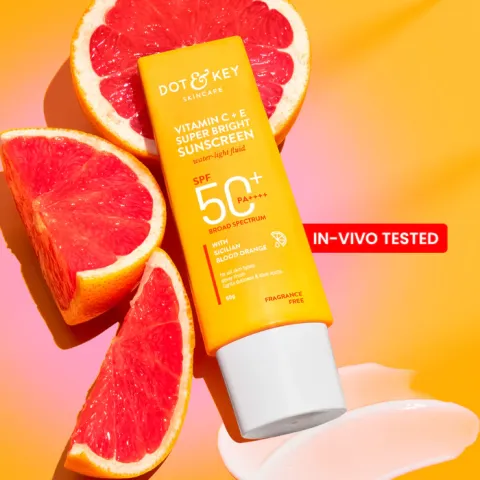 Yellow tube of sunscreen with grapefruit slices and a smear of cream on an orange background.