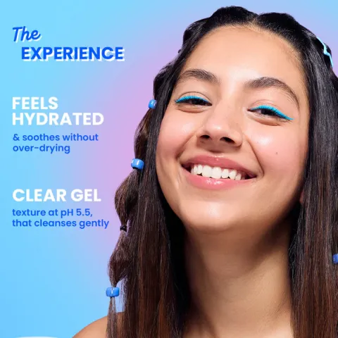 Young woman smiling with blue eyeliner and hair clips, on a blue gradient background.