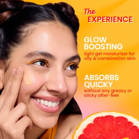 Smiling woman applying moisturizer to cheek with grapefruit slice in foreground on yellow background.