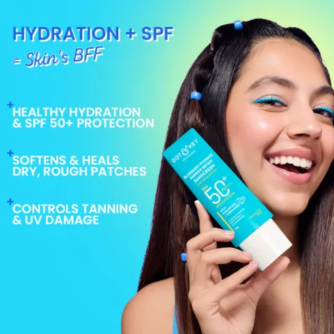 Smiling woman holding a blue tube of SPF moisturizer against a gradient blue-green background.