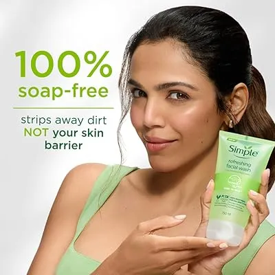 Woman in green top holding Simple face wash with a slight smile against a light background.