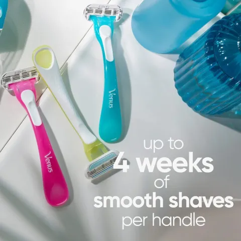 Three colorful Venus razors on a bright surface next to translucent blue objects.