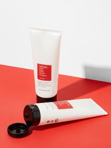 Two white cosmetic tubes with red labels on a red and white background.