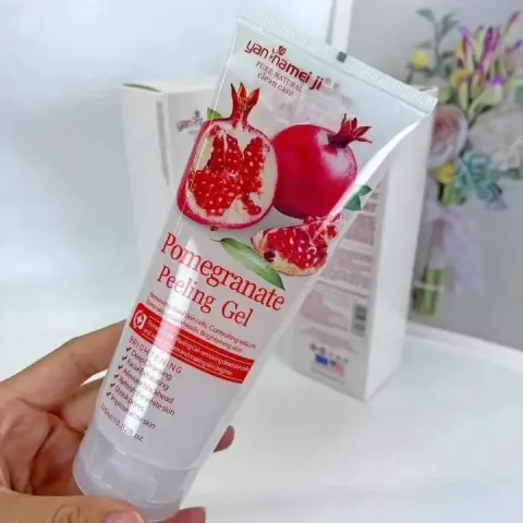 Hand holding a tube of pomegranate peeling gel with pomegranate images on the packaging.
