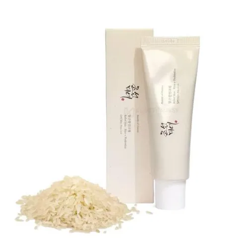 Beige skincare tube and box next to a small pile of rice.