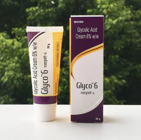 Tube and box of Glyco 6 glycolic acid cream displayed on a white surface with greenery behind.