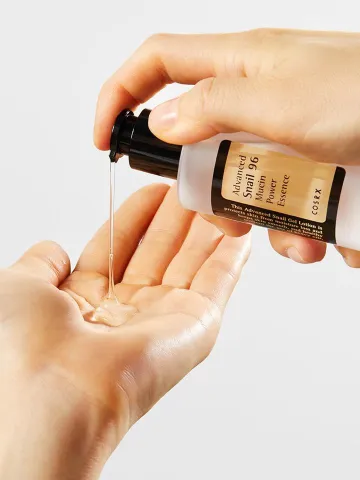 Liquid skincare product being dispensed onto a hand from a pump bottle.