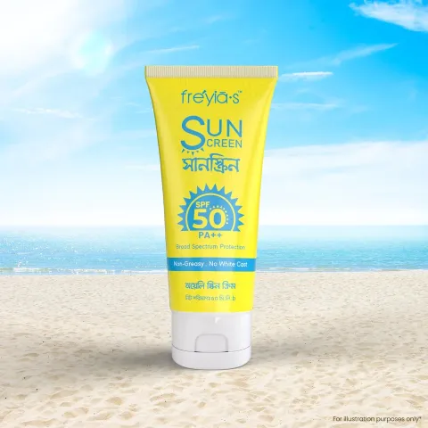 Yellow sunscreen tube with SPF 50 on sandy beach, blue sky and ocean in background.