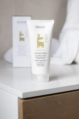 White skincare product tube with gold animal design on a white nightstand.
