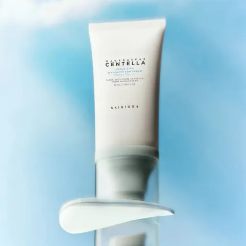 White skincare cream tube with a smear of product on a blue background.