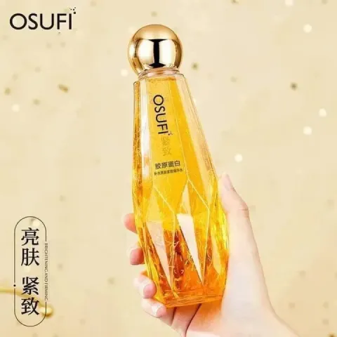 Hand holding a faceted golden OSUFI cosmetic bottle with a shiny round cap.