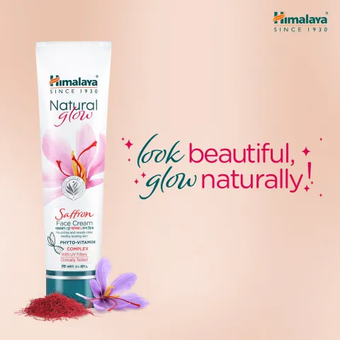 Himalaya face cream tube with saffron and flower on a soft pink background.