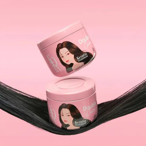 Two pink hair product jars on smooth, shiny black hair against a pink background.