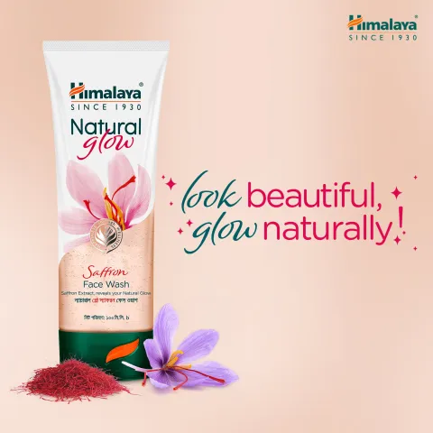 Himalaya Natural Glow face wash tube with saffron flower and powder on a peach background.