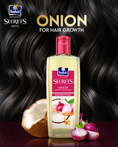 Hair oil bottle with coconut and onion against a background of shiny black hair.