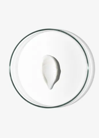 White cream dollop on a clear glass dish against a plain background.