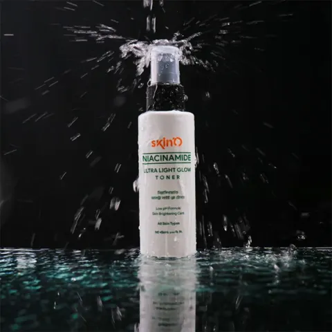 White cosmetic bottle with pump, splashed by water, on reflective surface against black background.