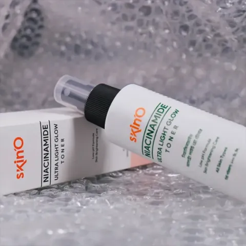 White bottle of Skino toner with matching box on bubble wrap background.