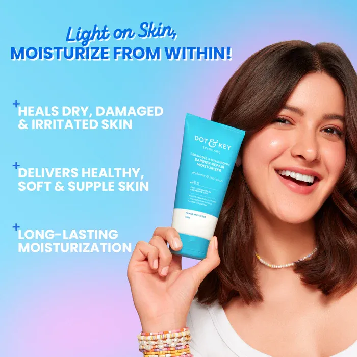 Smiling woman holding a blue skincare tube against a gradient blue and purple background.