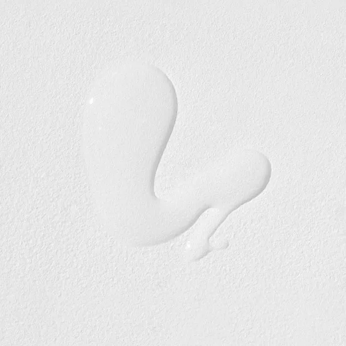A small drop of white liquid on a white textured surface.