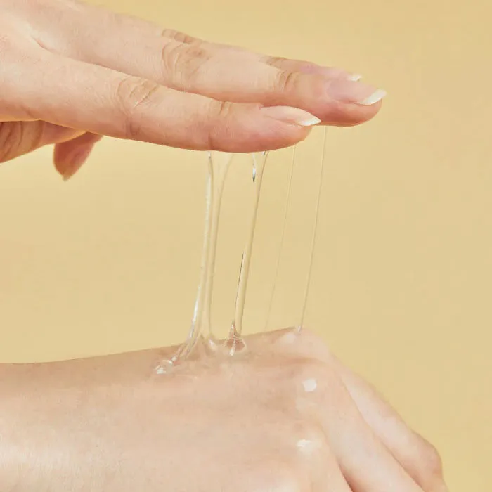 Clear gel being stretched between fingers and the back of a hand against a beige background.