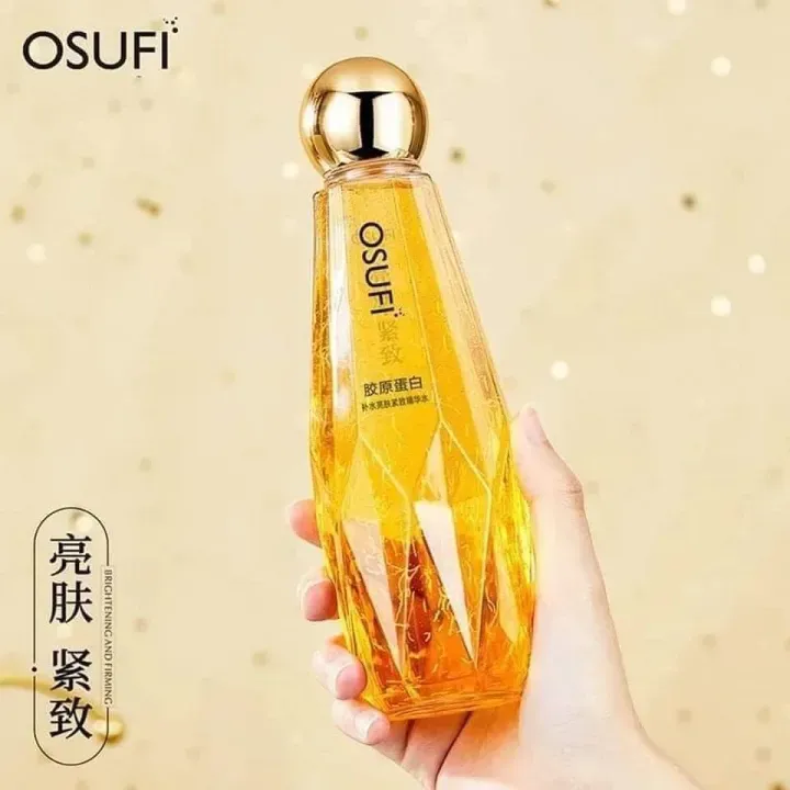 Hand holding a faceted golden OSUFI cosmetic bottle with a shiny round cap.