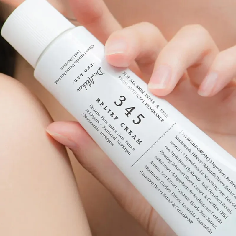 Hand holding a white tube of 345 Relief Cream with black text on the label.
