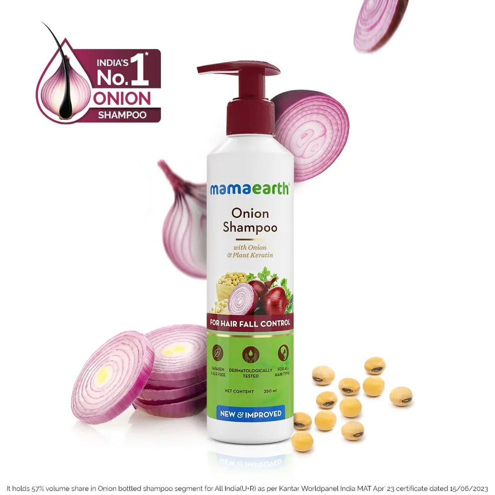 Mamaearth Onion Shampoo bottle with sliced red onions and yellow tablets around it.