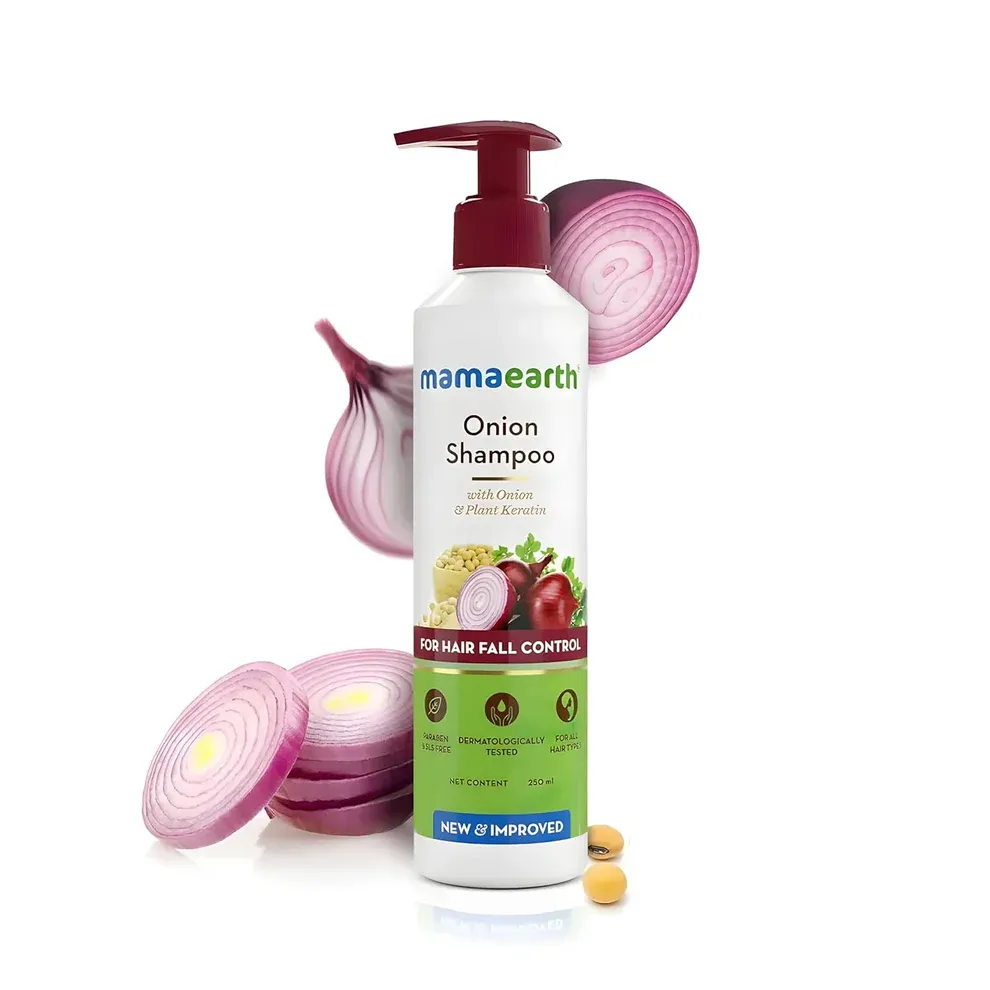 Mamaearth Onion Shampoo bottle with sliced red onions and capsules in the background.